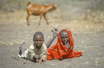Maasai children lying on the ground in front of their village, goat, Ngorongoro Crater, Tanzania,