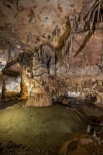 Stalactites and stalagmites, rock formations in a stalactite cave with water basin, Grotta del