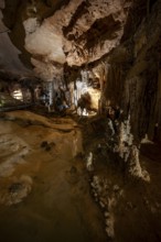 Stalactites and stalagmites, reflection in a small underground lake, rock formations in a