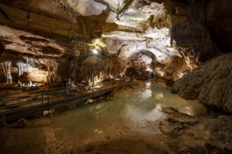 Stalactites and stalagmites, small underground lake and rock formations in a stalactite cave,