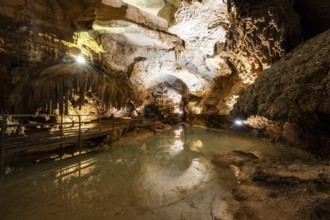 Stalactites and stalagmites, small underground lake, rock formations in a stalactite cave, Grotta