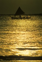 Fisherman with sailing cantilever tree at sunset, Bali, Indonesia