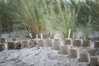 Sandcastle on the beach, detailed view of a sand castle with small towers and dug in the sand,