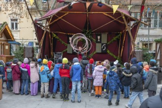A group of children watches an acrobat on stage, Historischer Christmas market am Neustädter church