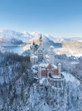 Neuschwanstein Castle in a wintry landscape with snow-covered mountains and blue sky, peaceful