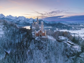 Fairytale castle Neuschwanstein in wintry evening, surrounded by snow-capped mountains, Schwangau