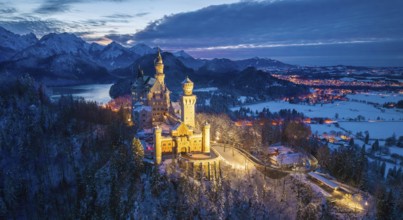 Panoramic view of Neuschwanstein Castle in snowy mountain landscape at dusk, night view, Schwangau