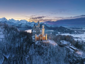 Picturesque Neuschwanstein Castle in winter at dusk with alpine panorama, Schwangau near Füssen,
