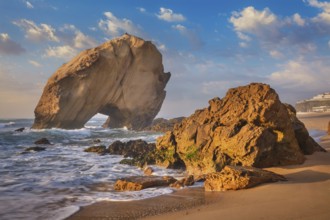 Penedo do Guincho, a large boulder rock arch at Praia da Santa Cruz, Portugal, with ocean waves and