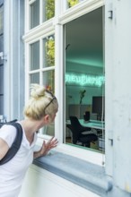 A woman looking at an office room, inscription Curious
