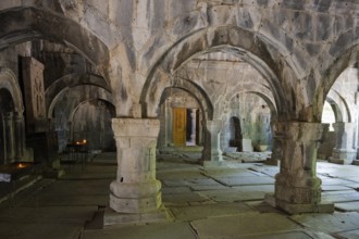 Ancient room with stone arches and yellow lighting creates a quiet, historic atmosphere, Sanahin