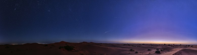 Starry sky over a desert-like landscape at dusk, Morocco, Sahara, in front of sunrise, panorama