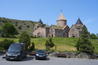 Historic monastery with stone buildings in a mountainous landscape with bright blue sky, Goshavank