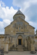Front view of a stone church with distinctive entrance and tower in front of sky, Haghartsin