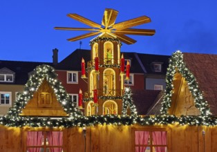 The Christmas market with the mulled wine pyramid in front of apartment buildings in the evening,