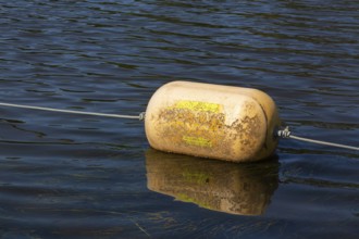 Yellow cautionary navigation buoy on river water surface serving to warn, signal or indicate of a