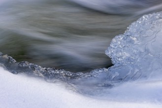 Ice formation formed by frost and freezing cold temperatures over running water of stream along