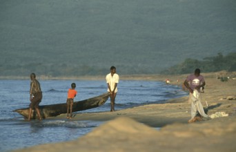 Men letting dugout into water, boy, Lake Malawi, Kande, Malawi, Africa, July 2000, vintage, retro,