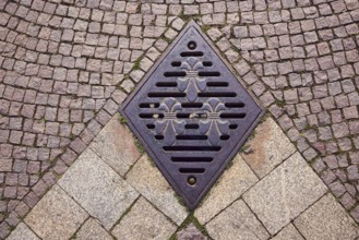 Manhole cover, city coat of arms, square made of paving stones and marble slabs, sunny, Wiesbaden,