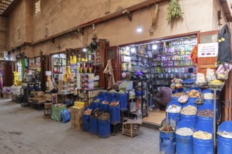 A colorful market stand full of spices, genes and products with a retailer inside a small shop,