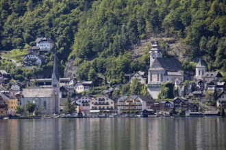 A, Hallstatt, A picturesque lakeside village with church in front of wooded mountains, Austria