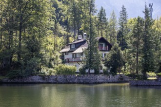 A, Hallstatt, A cozy house tucked away on the edge of a quiet lake surrounded by thick forest,