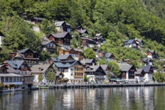 A, Hallstatt, lakeside village with numerous wooden houses, surrounded by lush greenery and