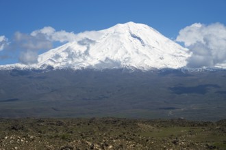 Impressive snow-covered mountain surrounded by clouds in a wide landscape, landscape near