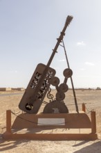 Metal sculpture of a giant guitar in the desert as an outdoor work of art