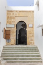 A stone staircase leads to an archway in a historic building