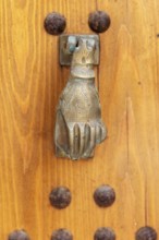 Hand-shaped metal knocker on a wooden door