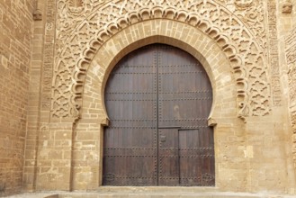 Large wooden gate with ornate stone carvings in an old wall