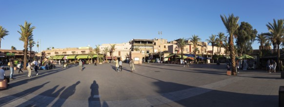 Bustling town square with palm trees and people in sunlight