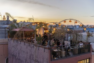 People relax on a lighted roof terrace during sunset