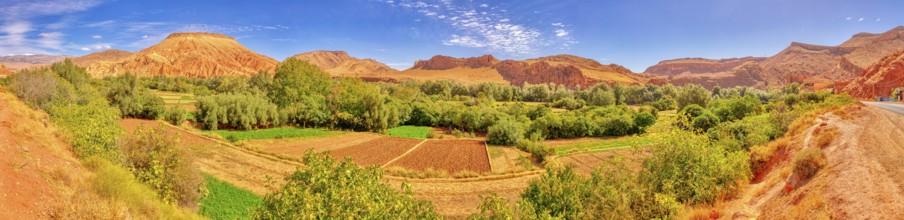A green landscape with mountains and a river under a clear blue sky