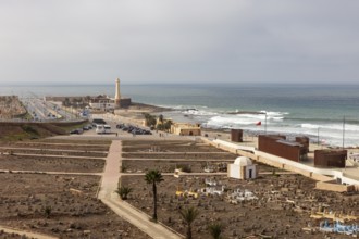Coastal landscape with lighthouse and waves at sea, cloudy sky