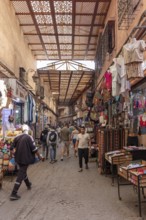 Covered market street with lots of people and colorful clothing stores
