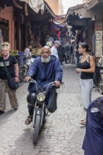 A vibrant street scenario in a Moroccan old town full of people and mopeds
