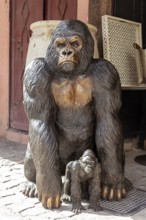 A large statue of a gorilla monkey with a young in a busy environment