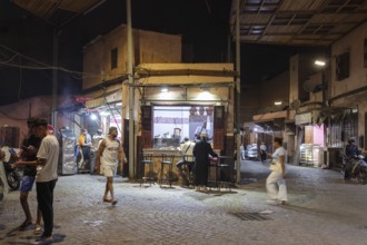 Night view of a busy street market with people and colorful lights in an old town atmosphere