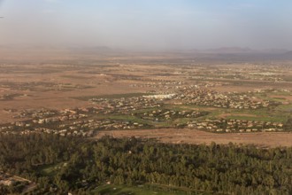 Aerial view of a vast landscape with green fields, trees and mountains in the background