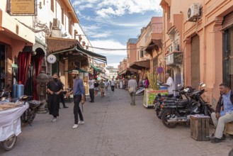 People stroll along a street with various shops