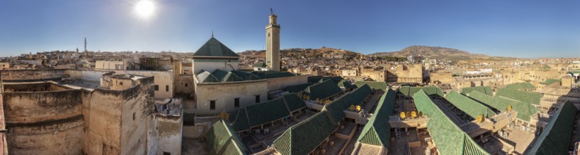 Extensive view of an old town with prominent green roofs and minaret