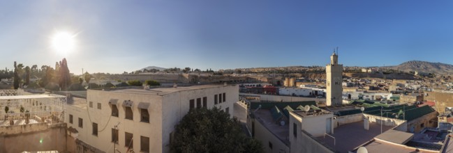 Panoramic view of an urban landscape with minaret and hilly background