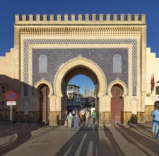 Large traditional gate with blue mosaic and people walking through