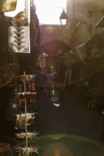 An atmospheric play of light and shadow in a narrow, sunny market alley