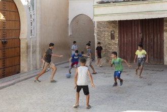 Children play soccer in a narrow alley. Carefree summer atmosphere