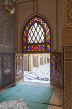 A sumptuous interior with a colorful stained glass window that throws light into the room in