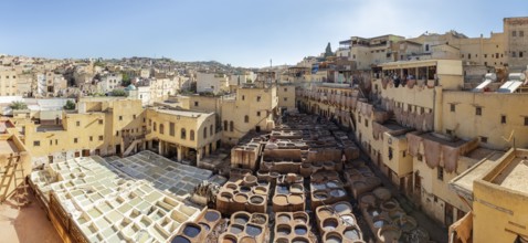 A wide view of a traditional Moroccan tannery in the middle of the lively cityscape with buildings