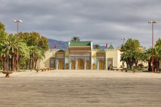 Large palace complex with arches and palm trees in a spacious courtyard